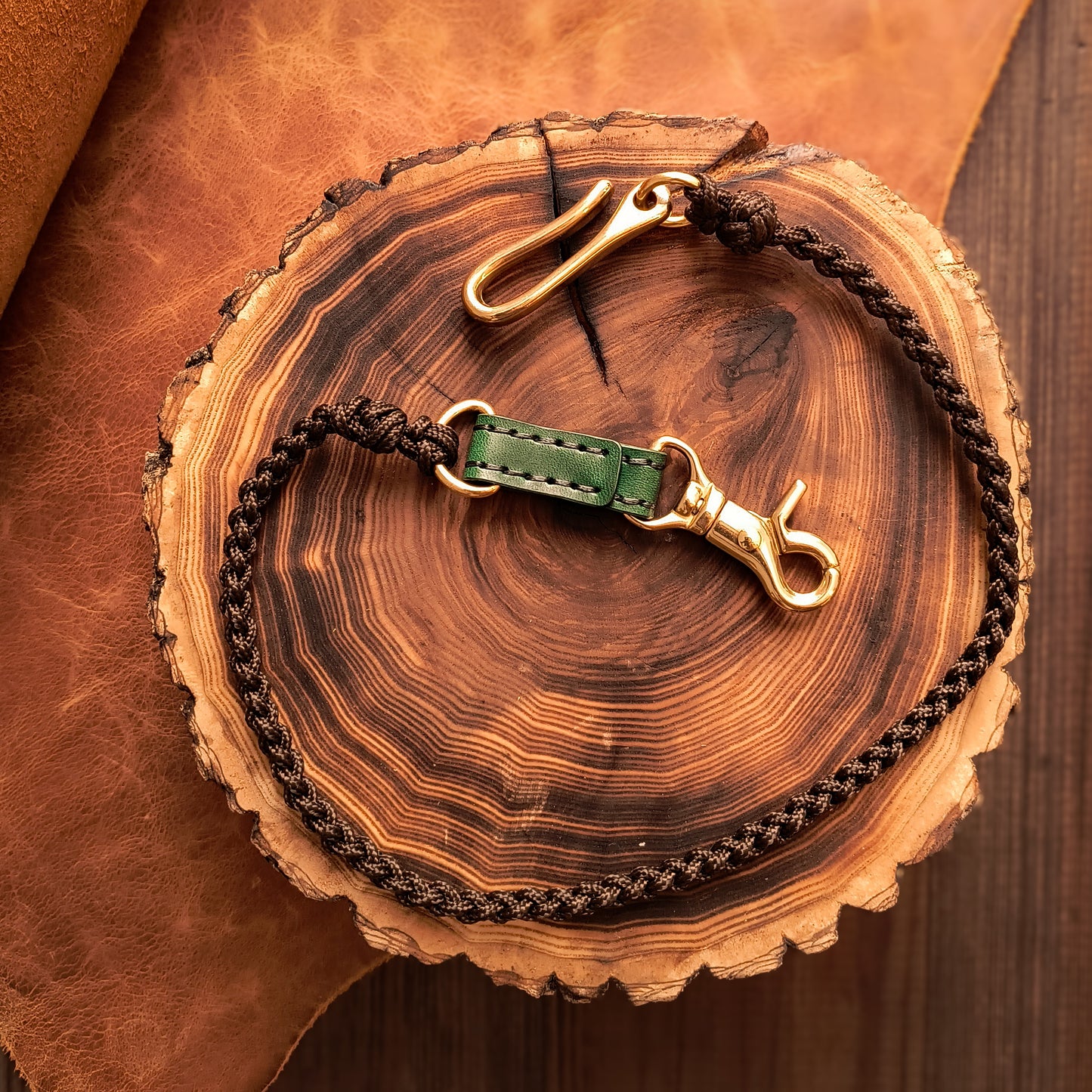 Fully hand braided lanyard with chocolate-colored paracord strap, deep green leather details and solid brass hardware 