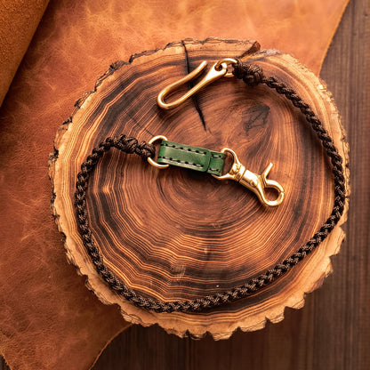 Fully hand braided lanyard with chocolate-colored paracord strap, deep green leather details and solid brass hardware 