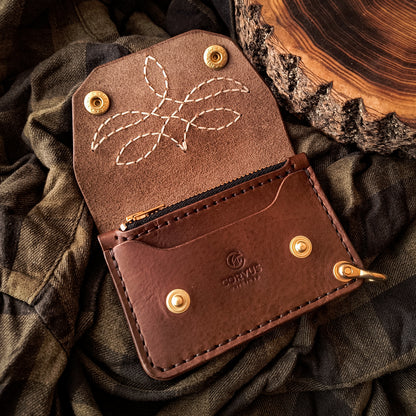 Small leather trucker wallet with decorative hand-stitched pattern on flap and two solid brass snap buttons